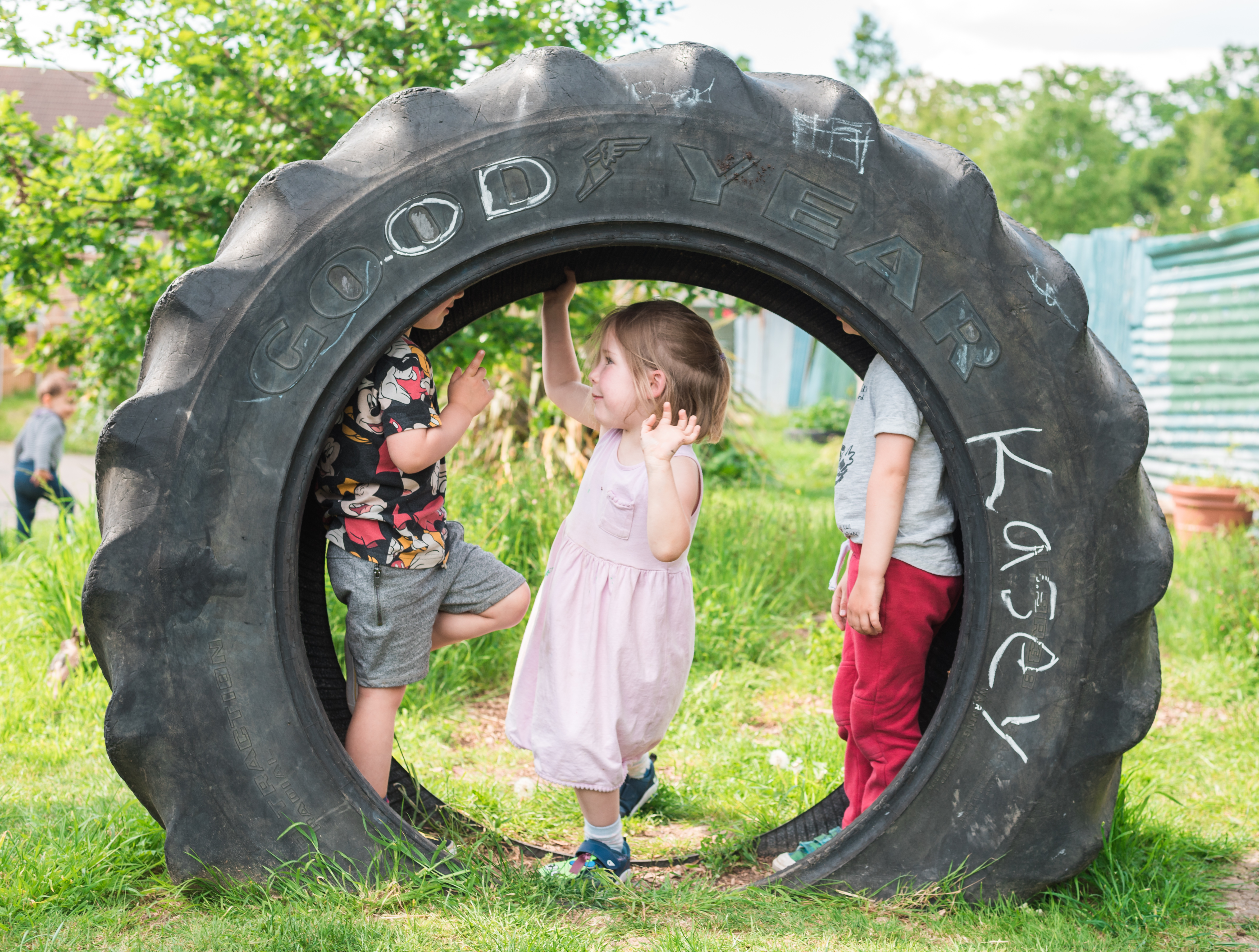a little girl plays inside a tractor wheel in a playground