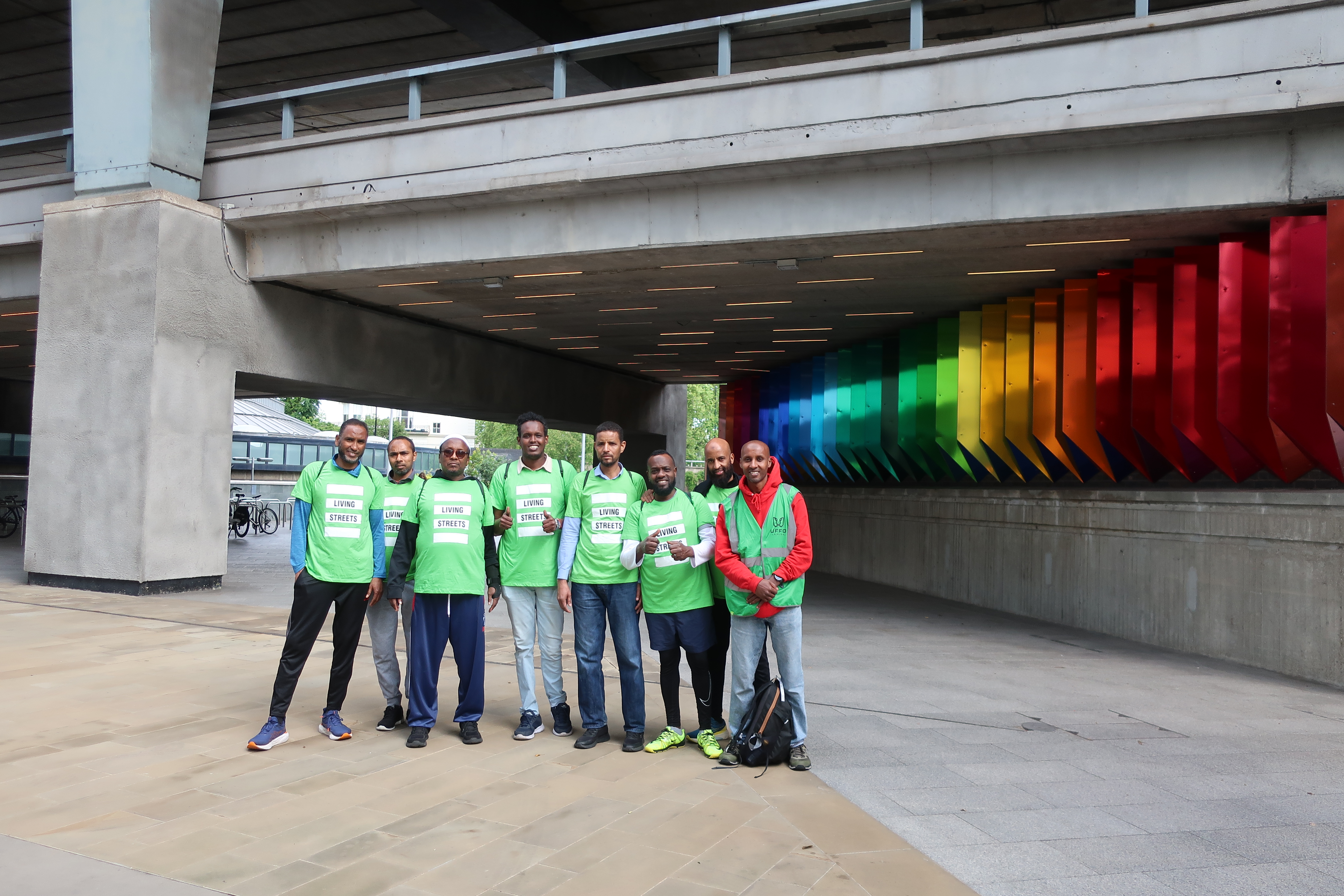men stand in an underpass with green living tshirts on