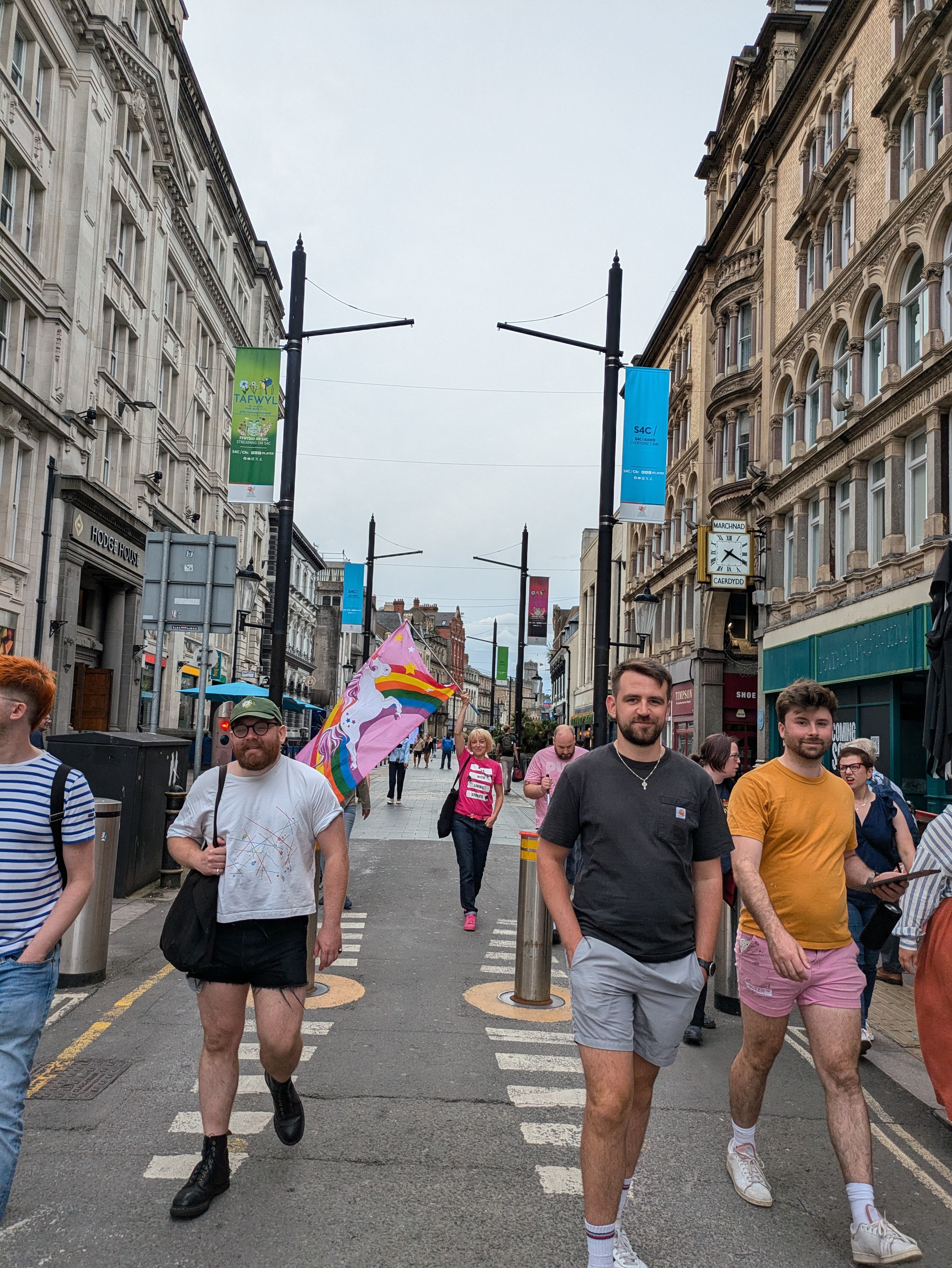 A group of people are walking down a busy street in Cardiff