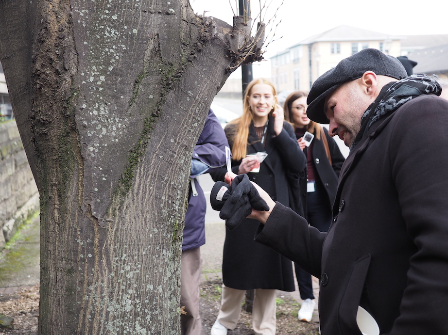A man uses an indicator to look at a tree to test for air quality