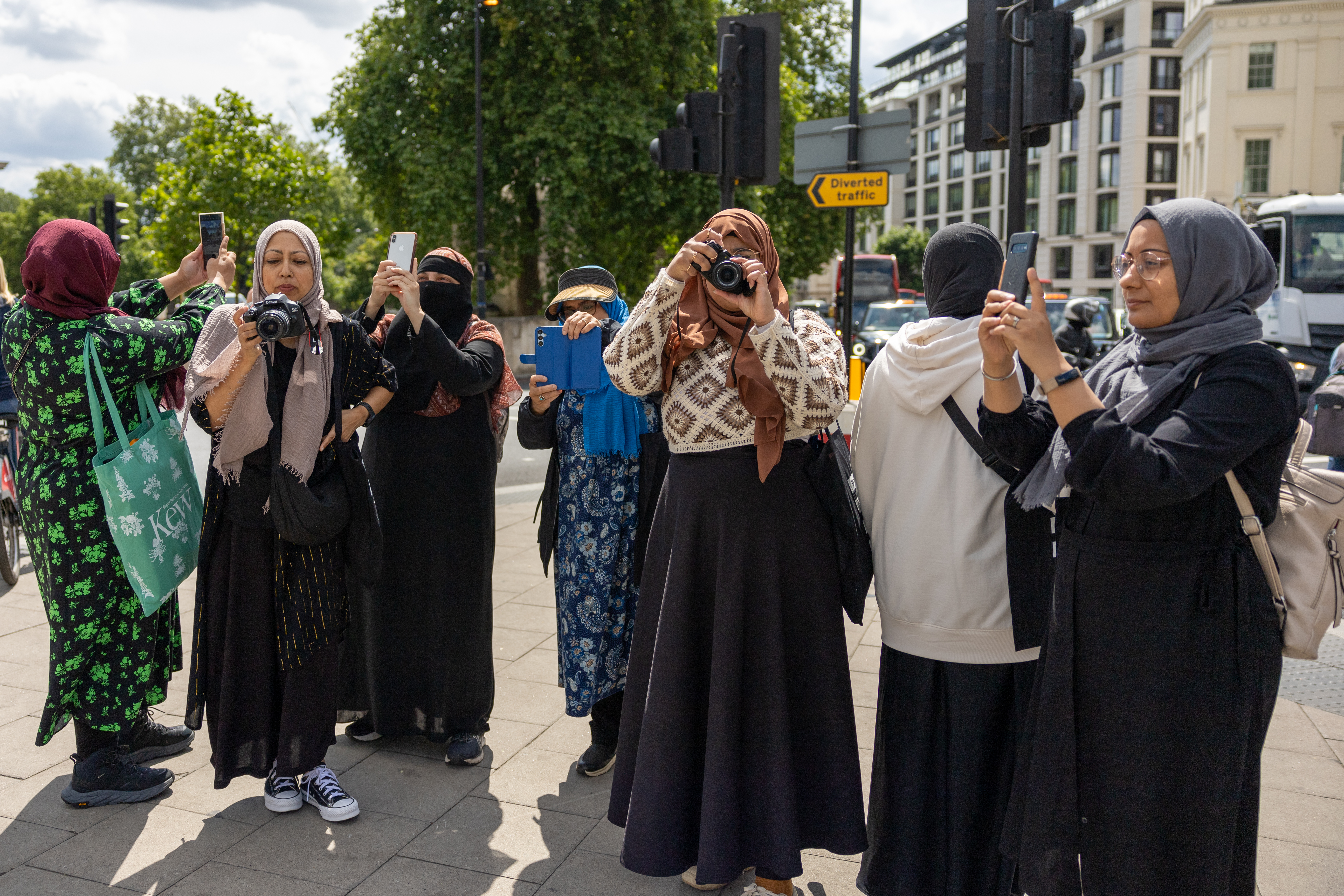 Several women in hijabs and burkhas stand with cameras in their hand