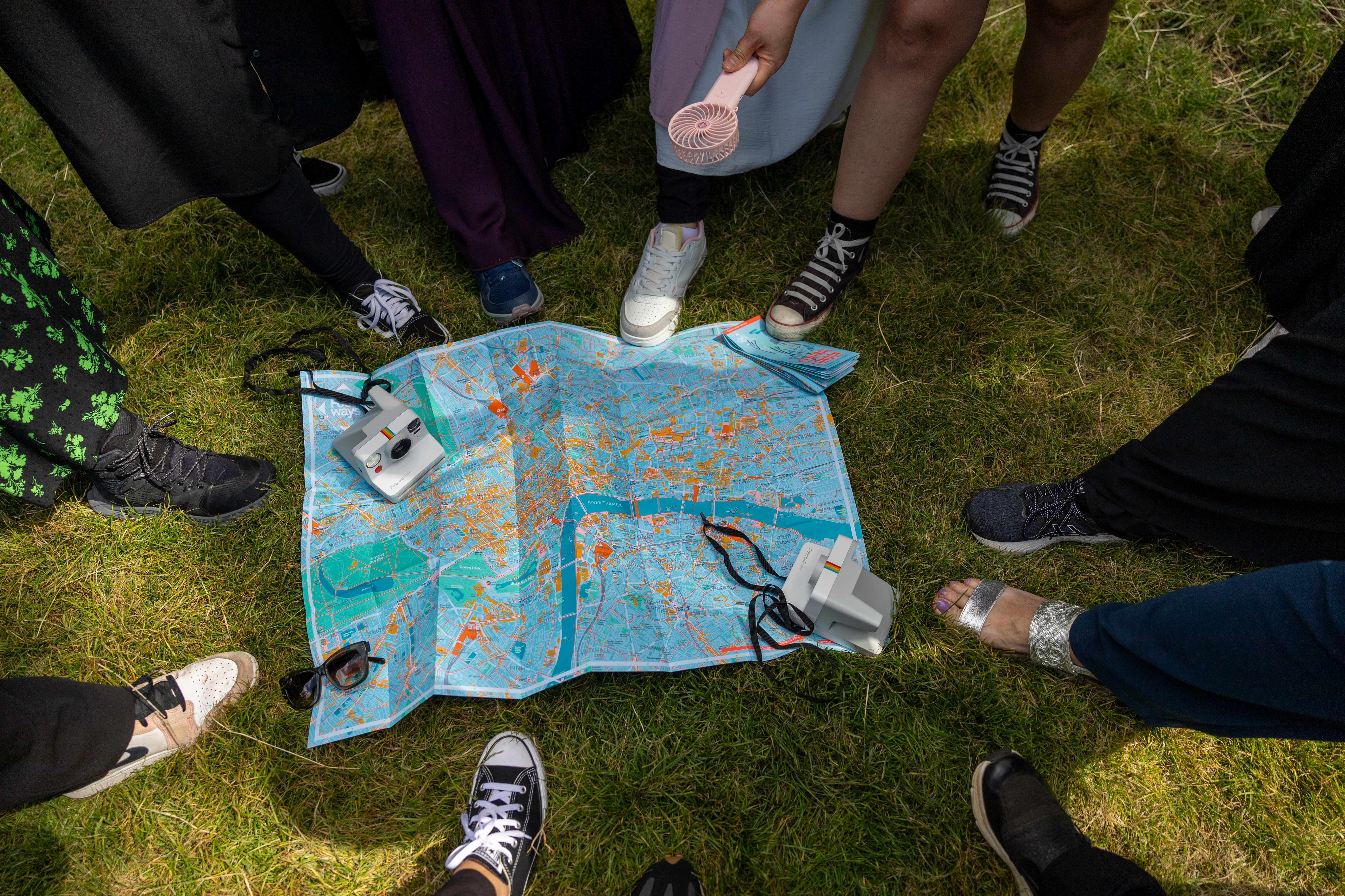 Many feet are touching a map on the grassy floor