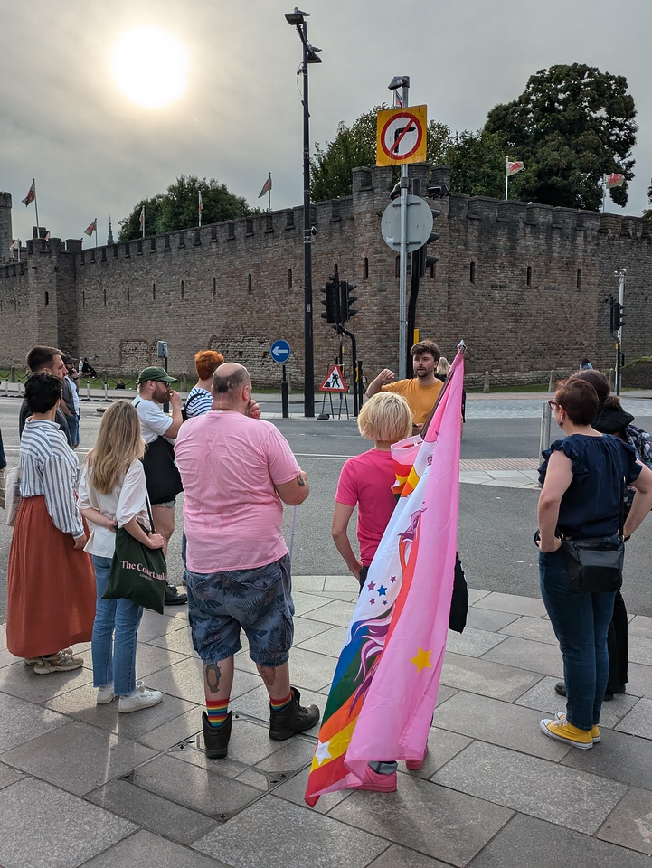 Cardiff Castle is in the background as a man talks to to a group on the street