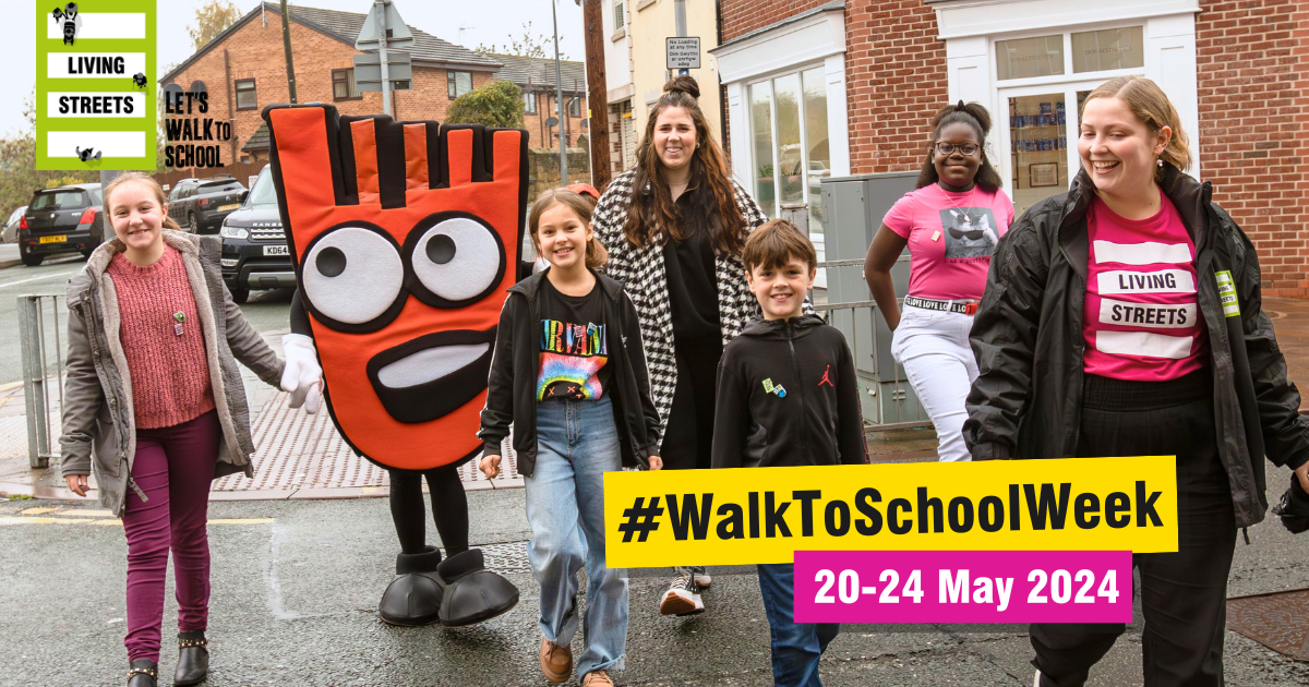 A group of children and adults walk to school with Living Streets mascot Strider